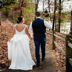 Bride and groom walking away along a leaf-covered path in the fall