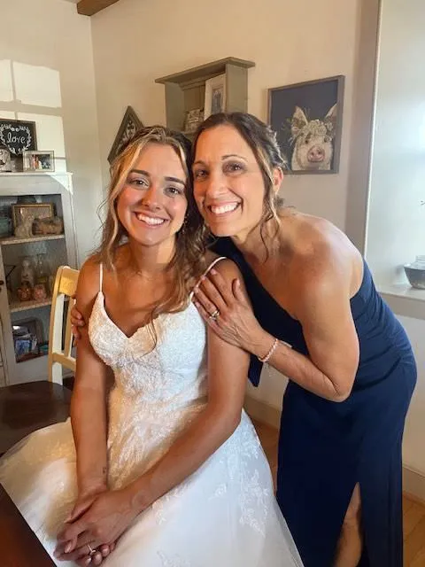 Smiling bride sitting with a woman in a navy dress before the wedding