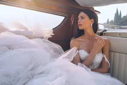 Bride in a strapless gown with a full tulle skirt sitting in the back of a vintage car