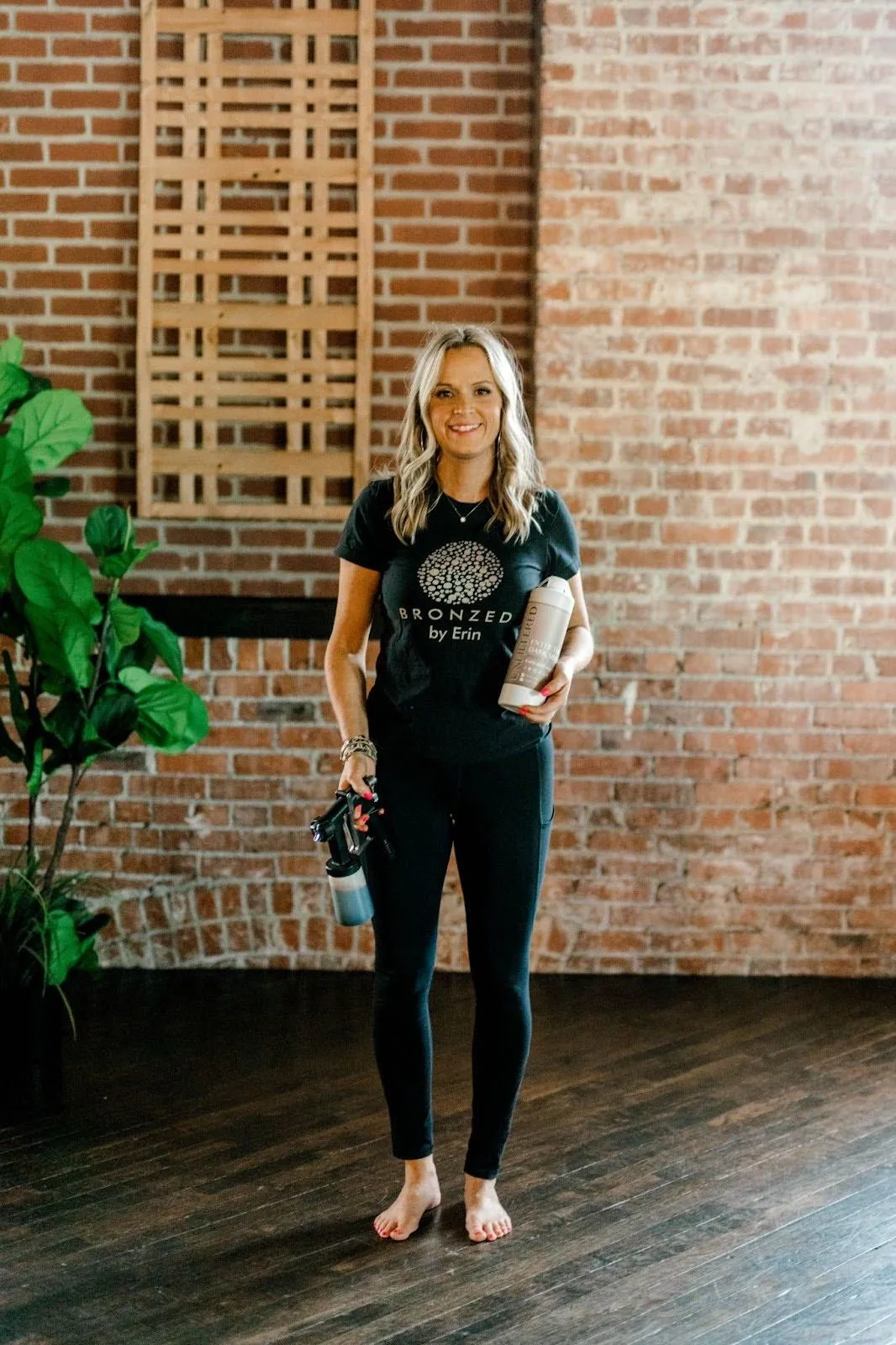 Erin Custer in a black t-shirt standing in front of a brick wall