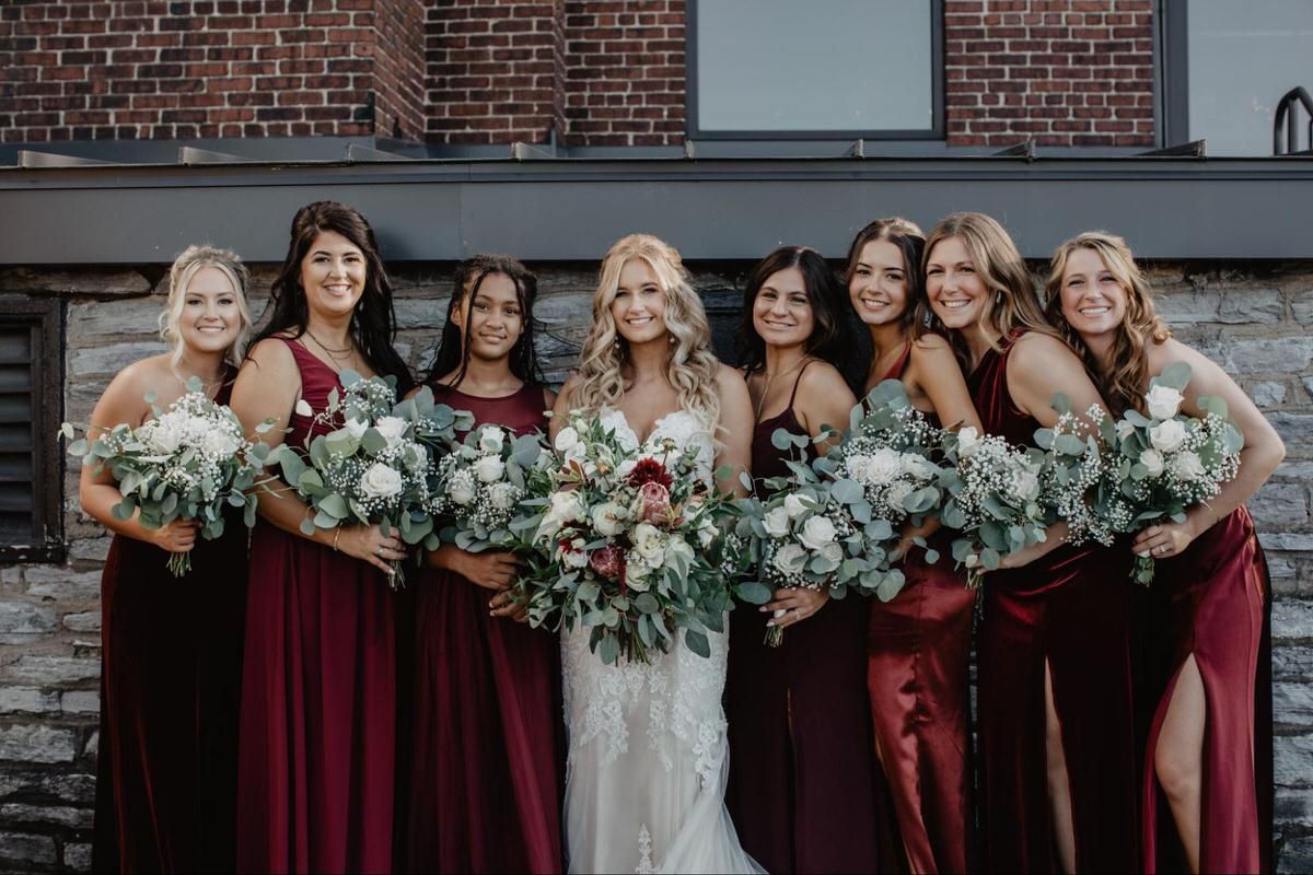 Bride with her bridesmaids in burgundy dresses holding bouquets